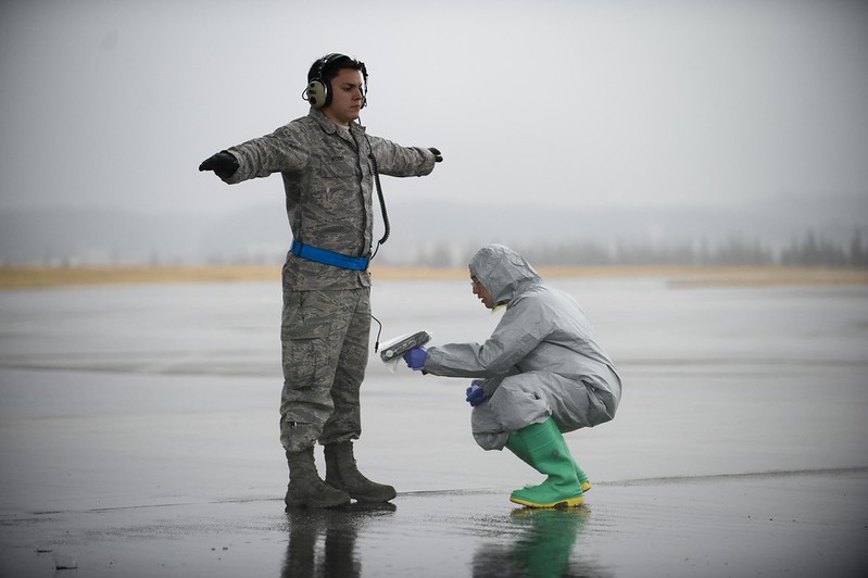 a contamination clean up worker being tested by another worker on a beach